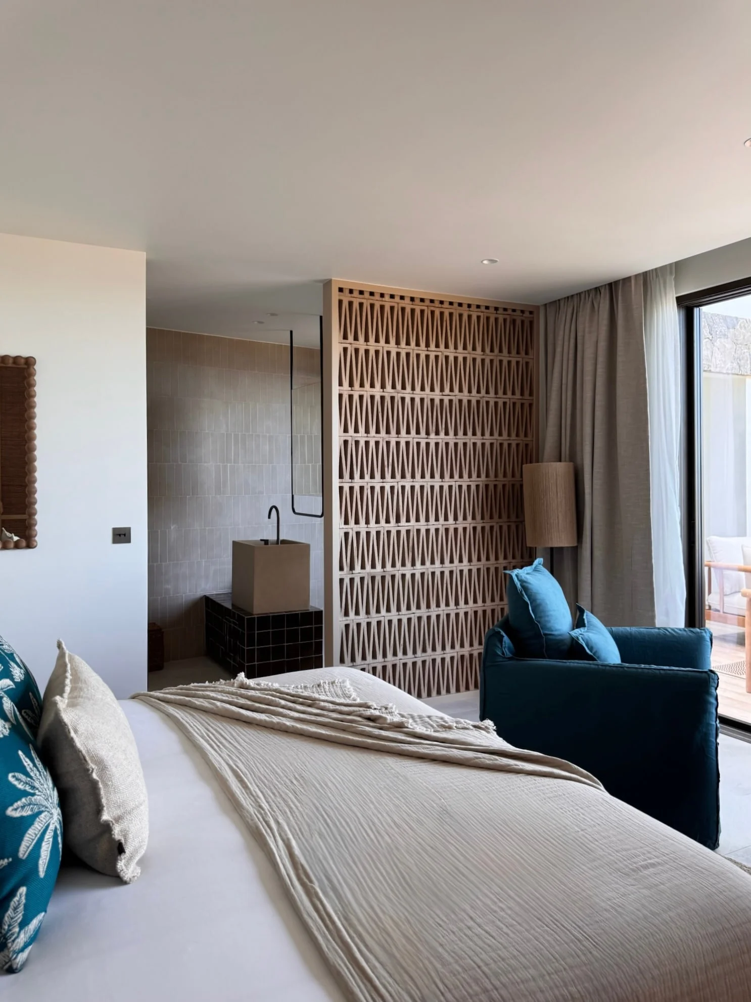 Bedroom with carved wooden screen and blue armchair — Anse des Cayes, Saint Barthélemy