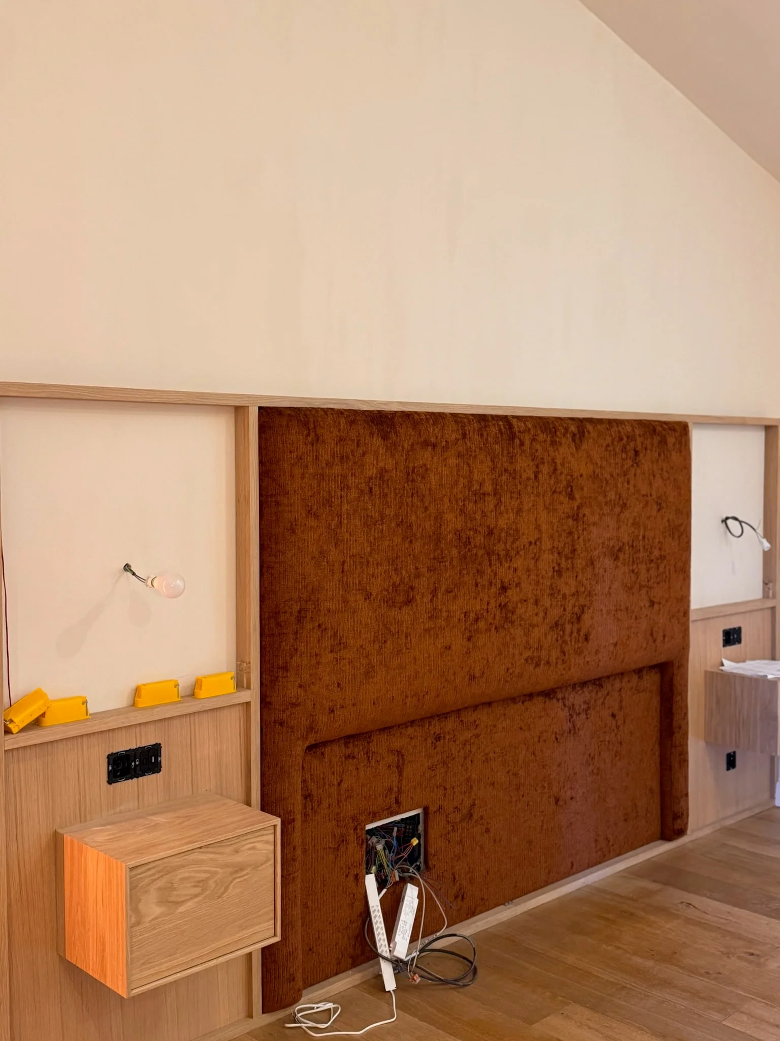 Upholstered headboard and wooden bedside units during installation