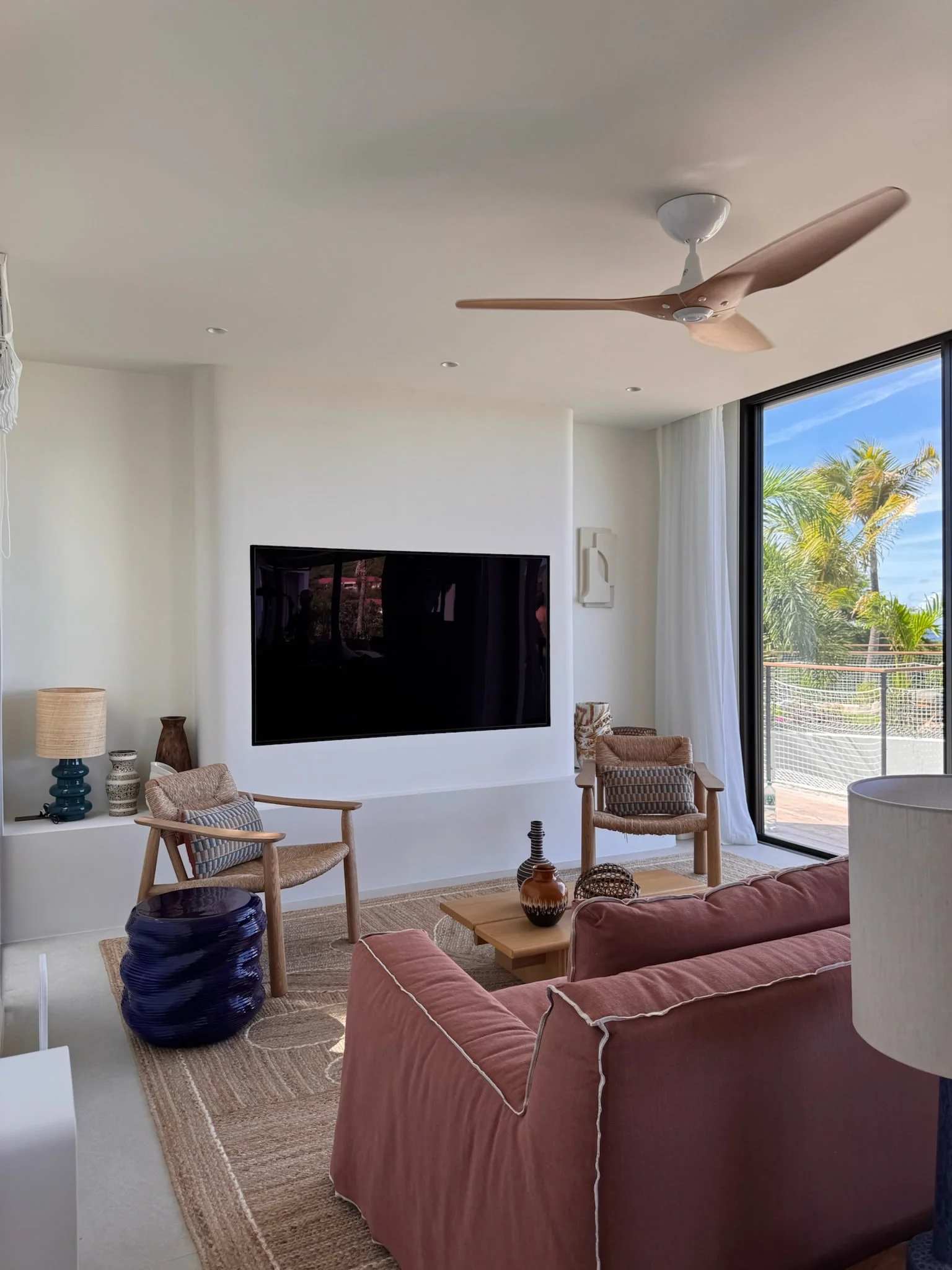 Living room with pink sofa, ceiling fan and view of the garden — Anse des Cayes