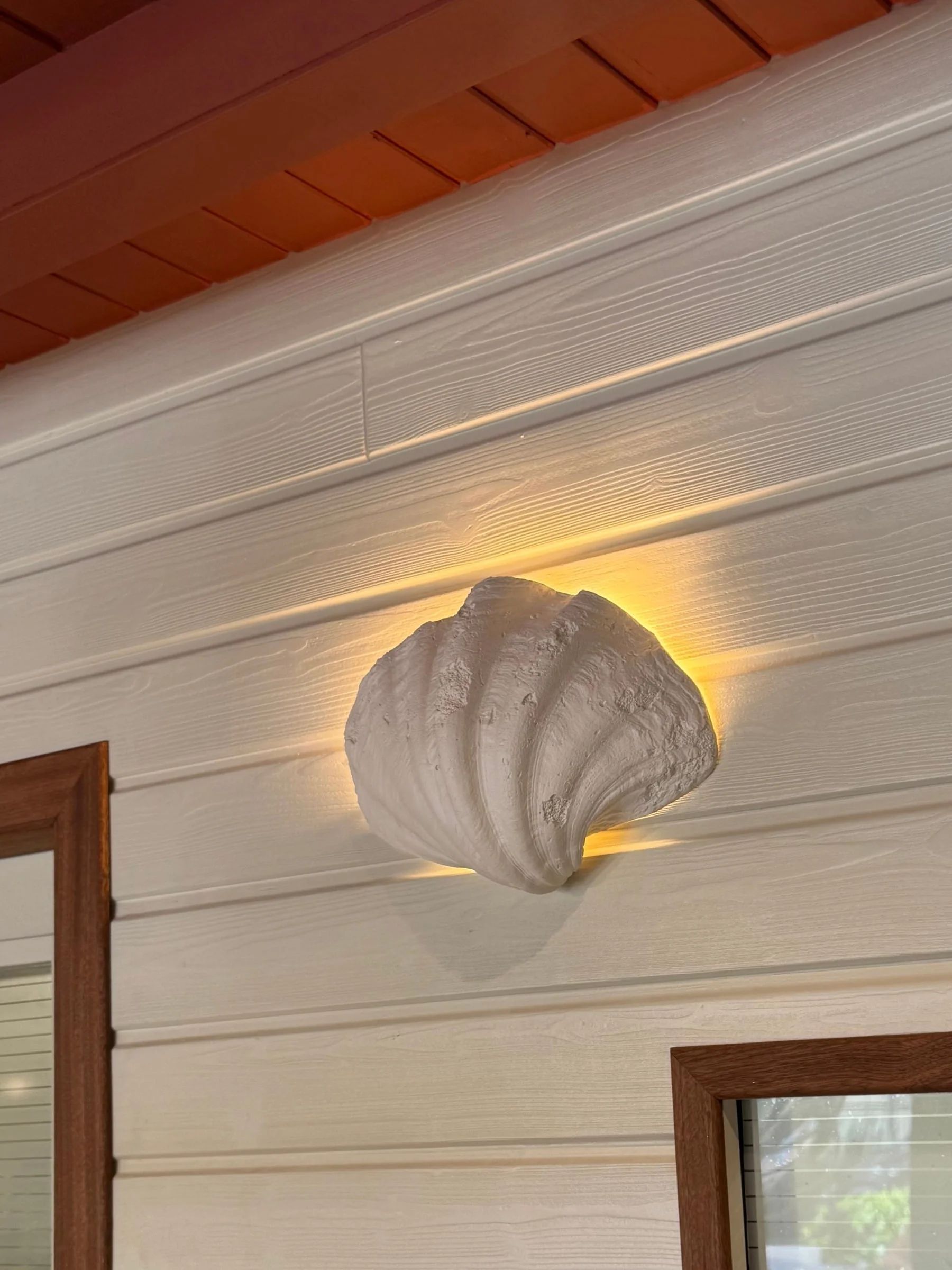 Shell wall light on white timber cladding — Dado Café