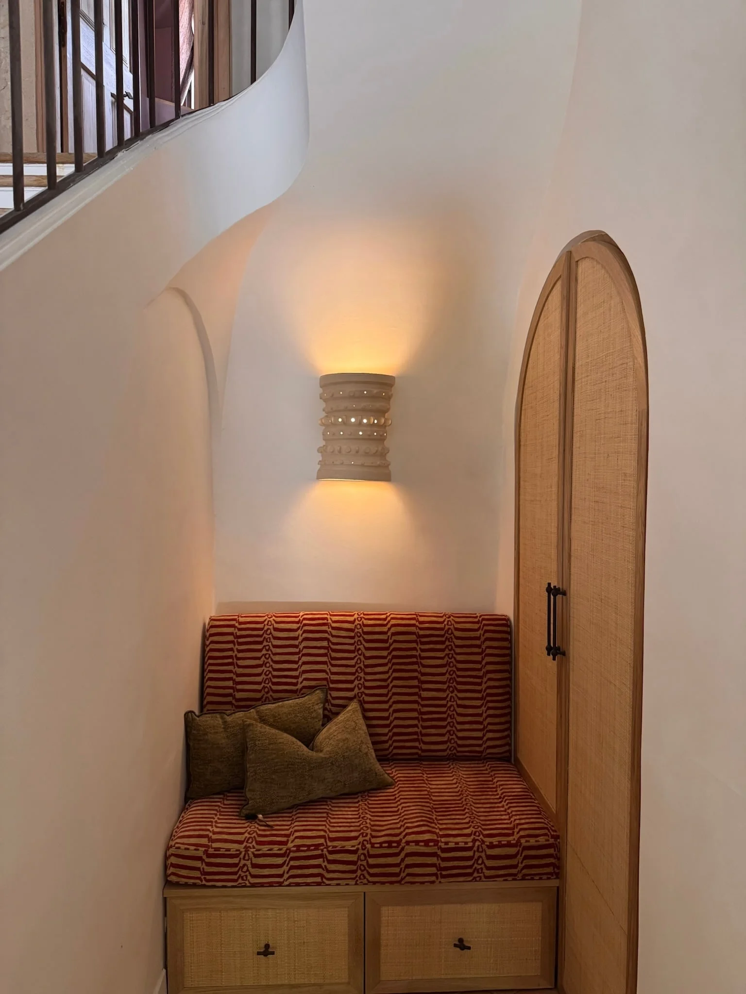 Arched niche with a bench seat and wall light beneath the stairs — Fontaine