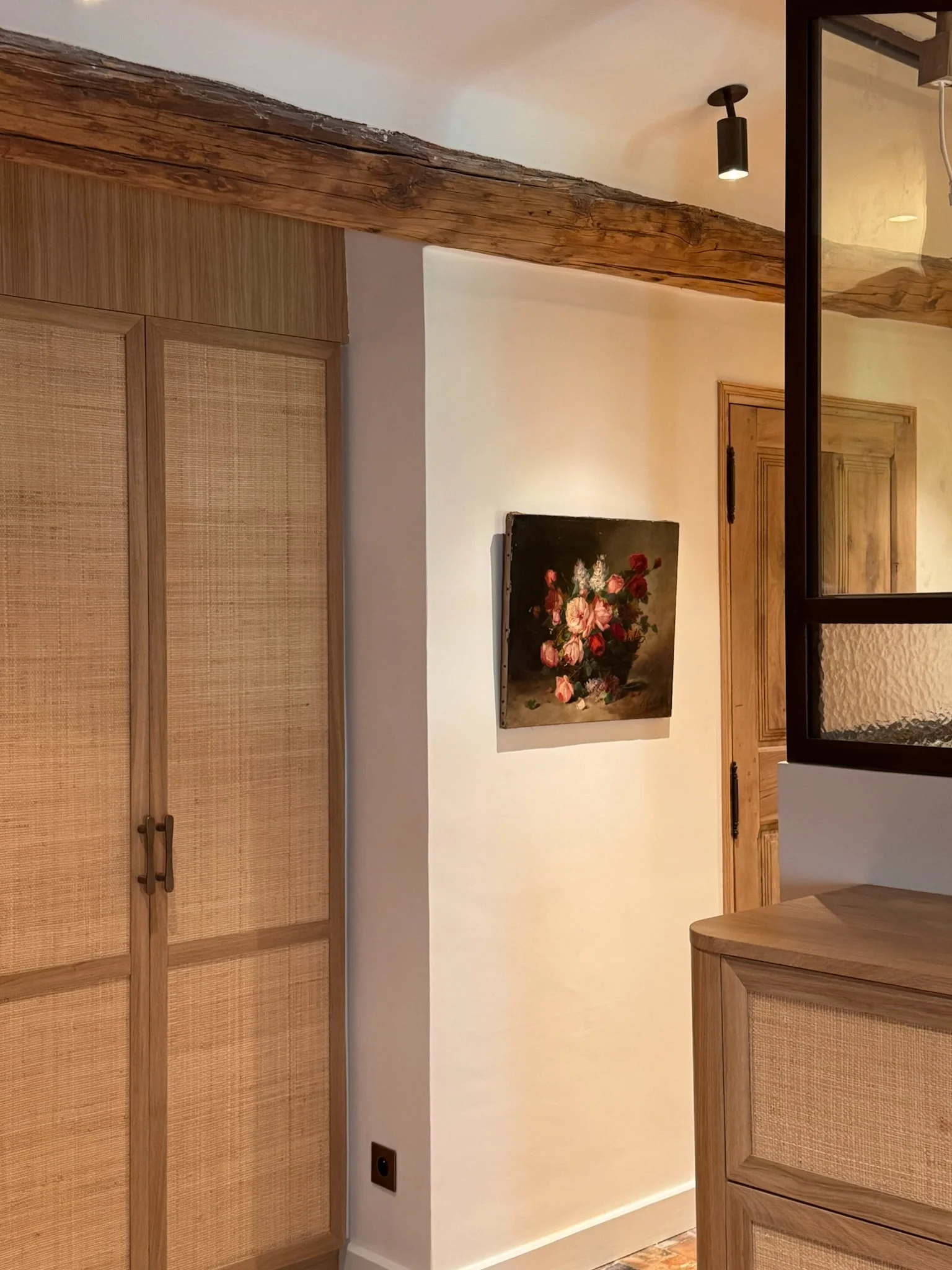 Cane-fronted wardrobe and still-life painting in a hallway — Fontaine