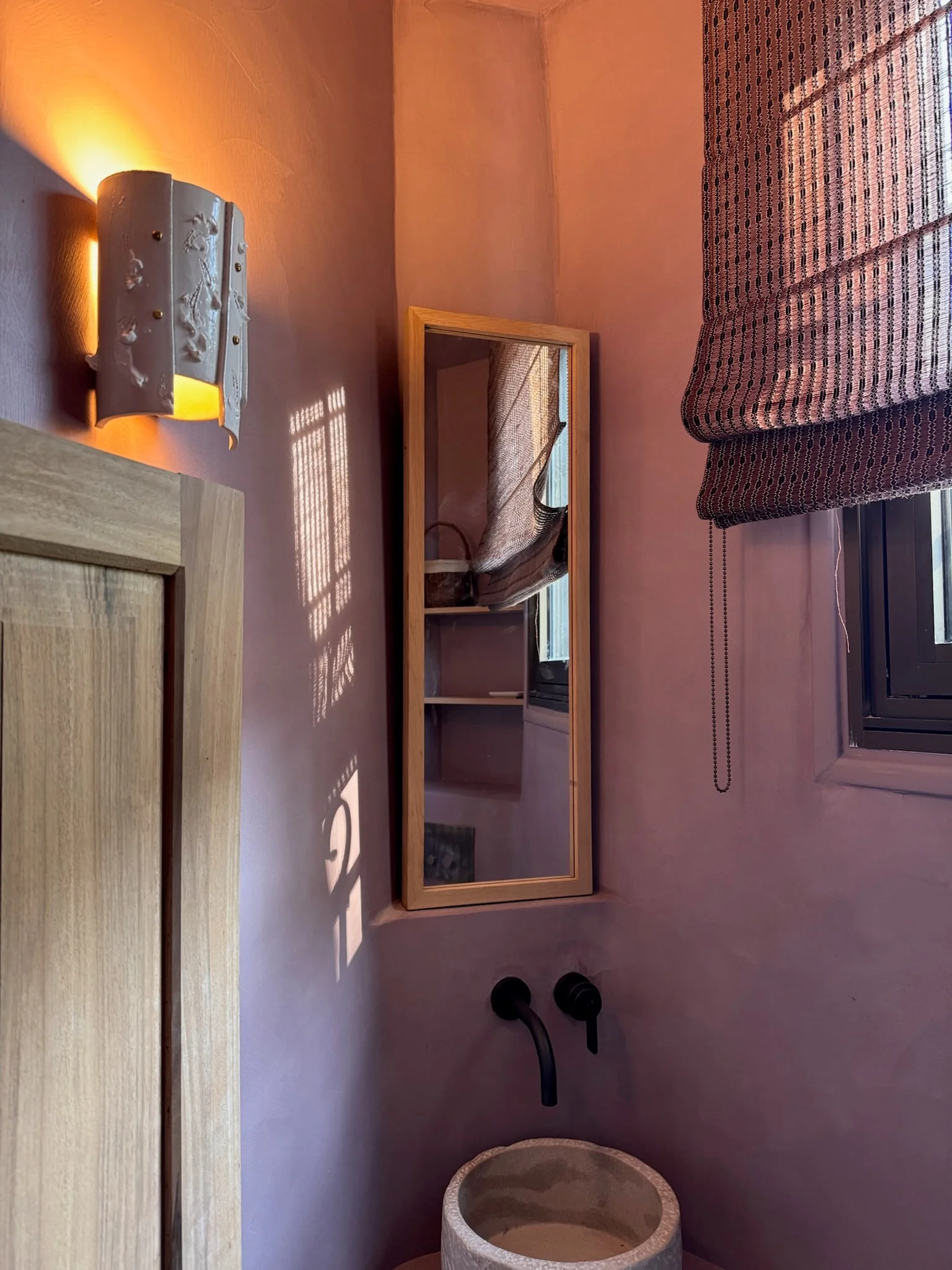 Pink plastered shower room with wall light and narrow mirror — Fontaine