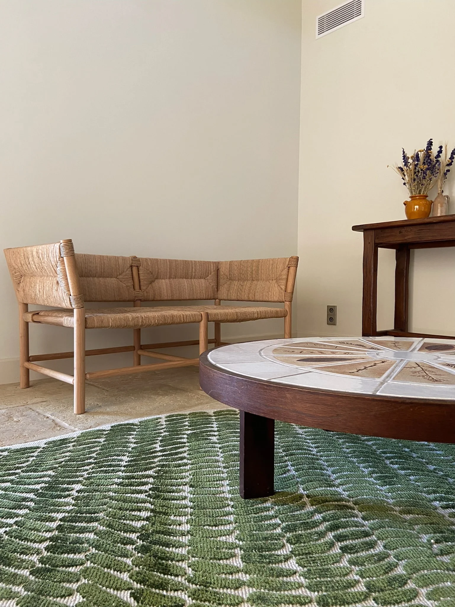 Rattan sofa, tiled coffee table and green rug — Montjoie