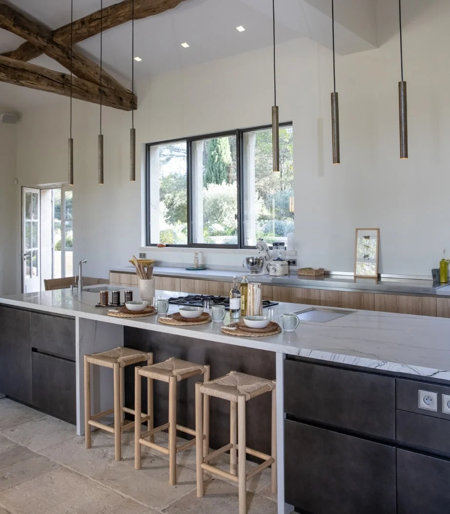Kitchen island with wooden stools beneath exposed beams — Montjoie