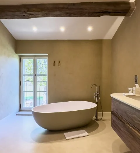 Freestanding bathtub beneath an exposed beam — Montjoie