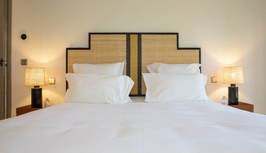 Bed with cane headboard and pleated lamps — Montjoie