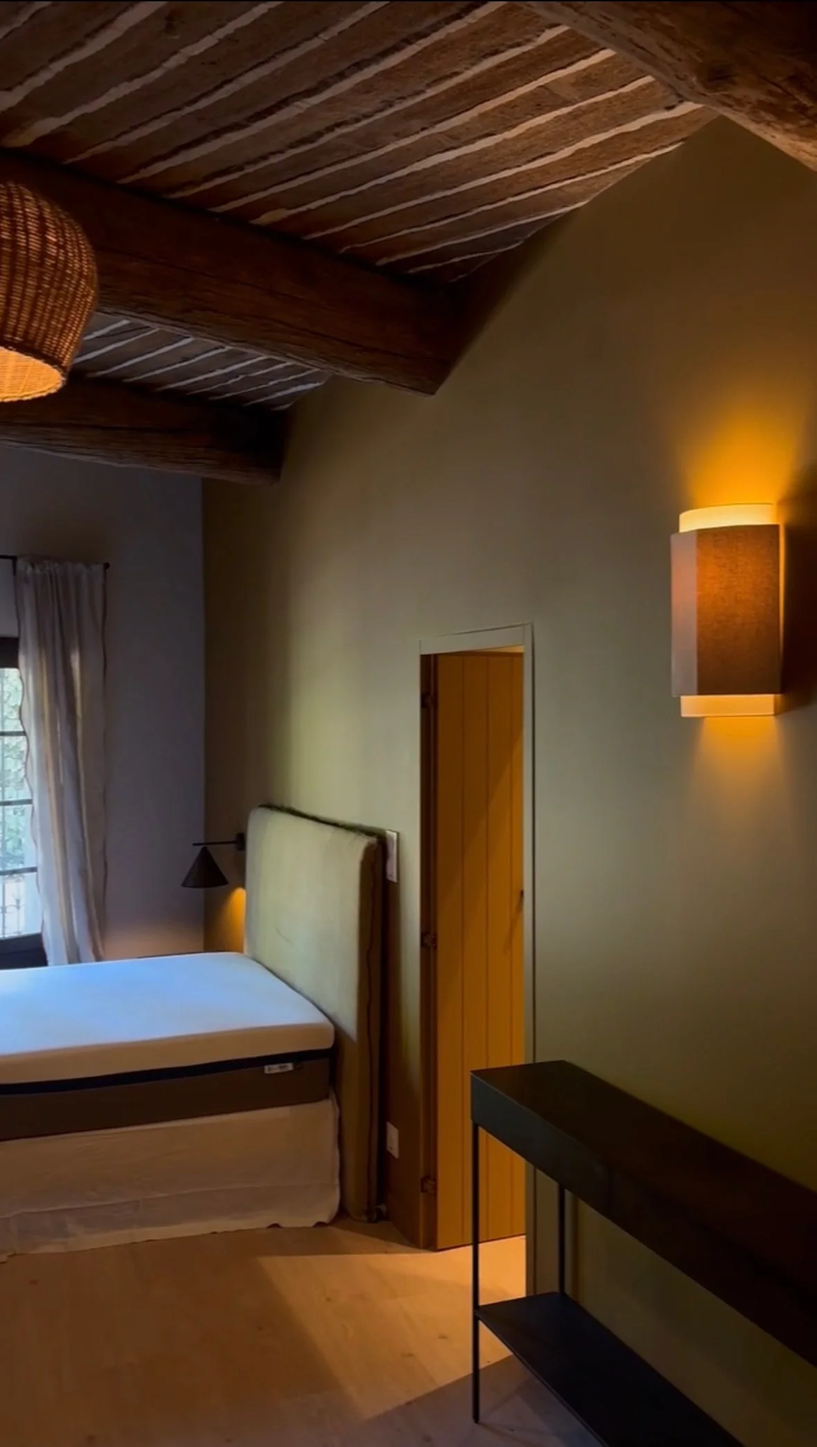 View of the studio, with the bed and a wall light — Petite Fontaine